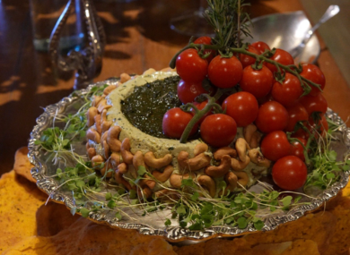 Patê decorado com castanhas de caju, ao lado de tomates-cereja e ervas frescas